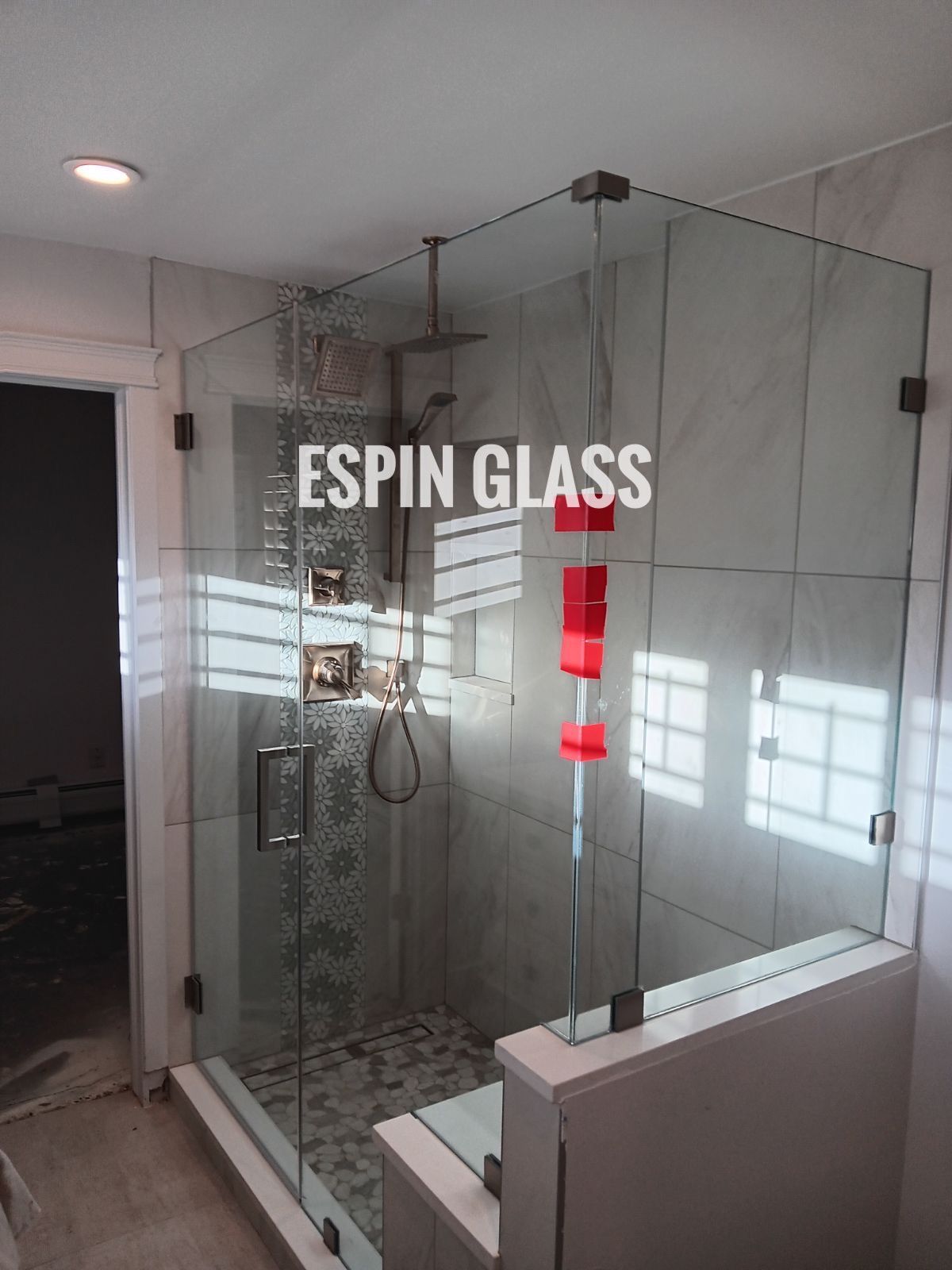 Frameless glass shower enclosure in a bathroom with tile walls and a bench.