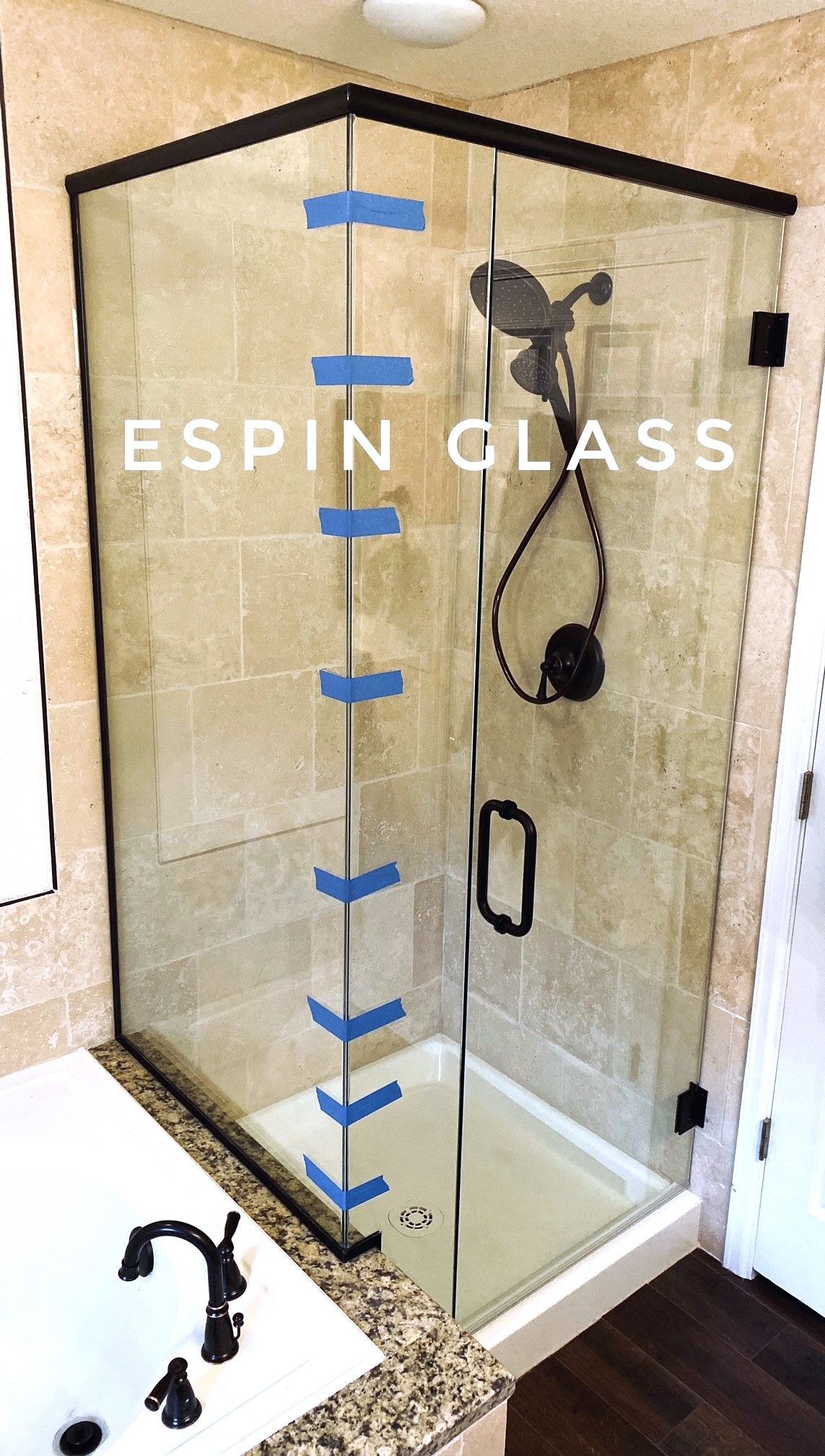 Framed glass shower enclosure with black hardware. The shower has a black showerhead and a black handle. 