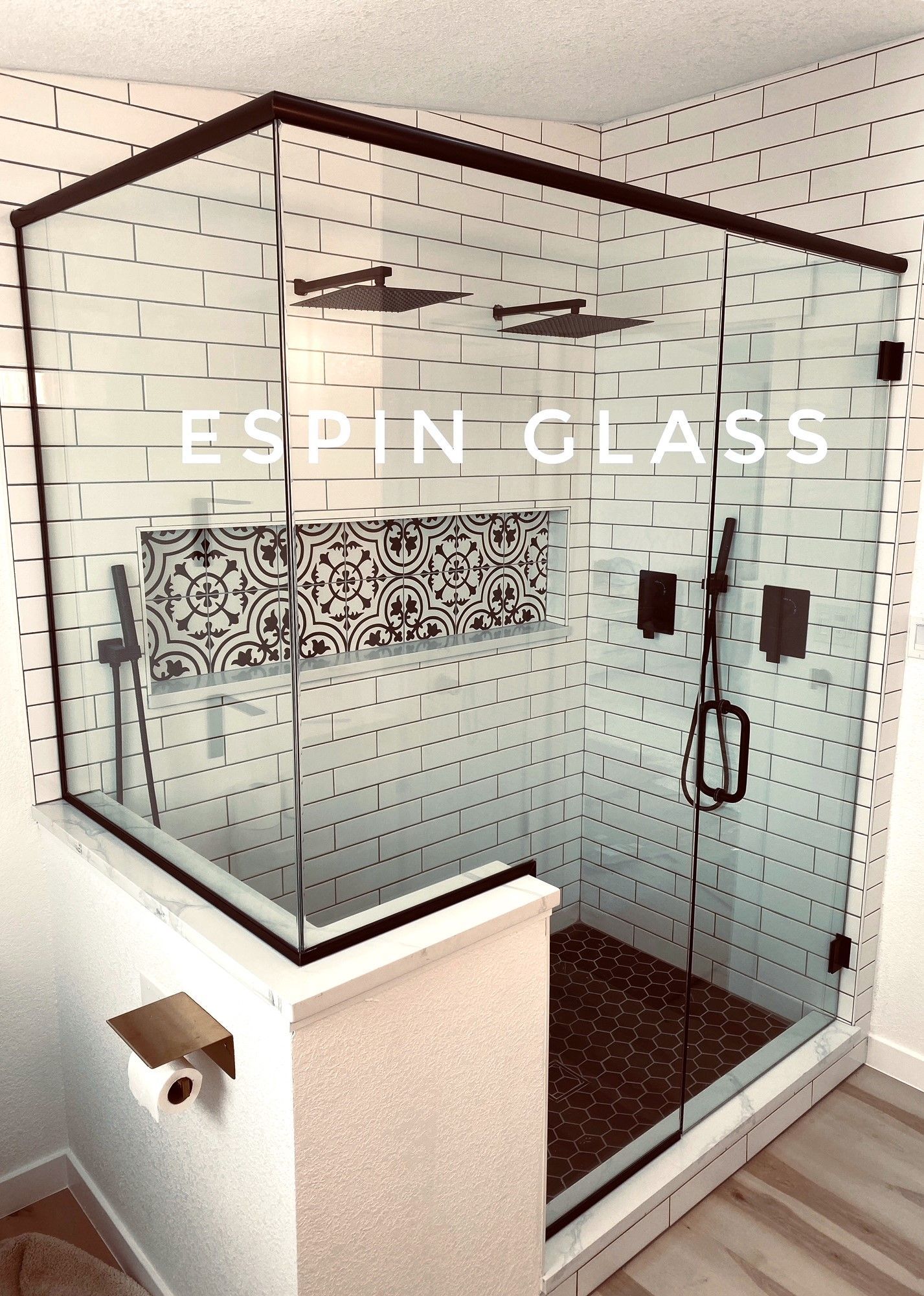 Black-framed glass shower enclosure with subway tile walls and patterned niche.