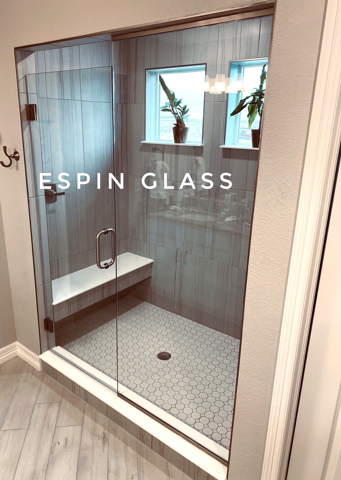 Shower with glass doors, white bench, and stone tile floor. Includes small windows with plants.