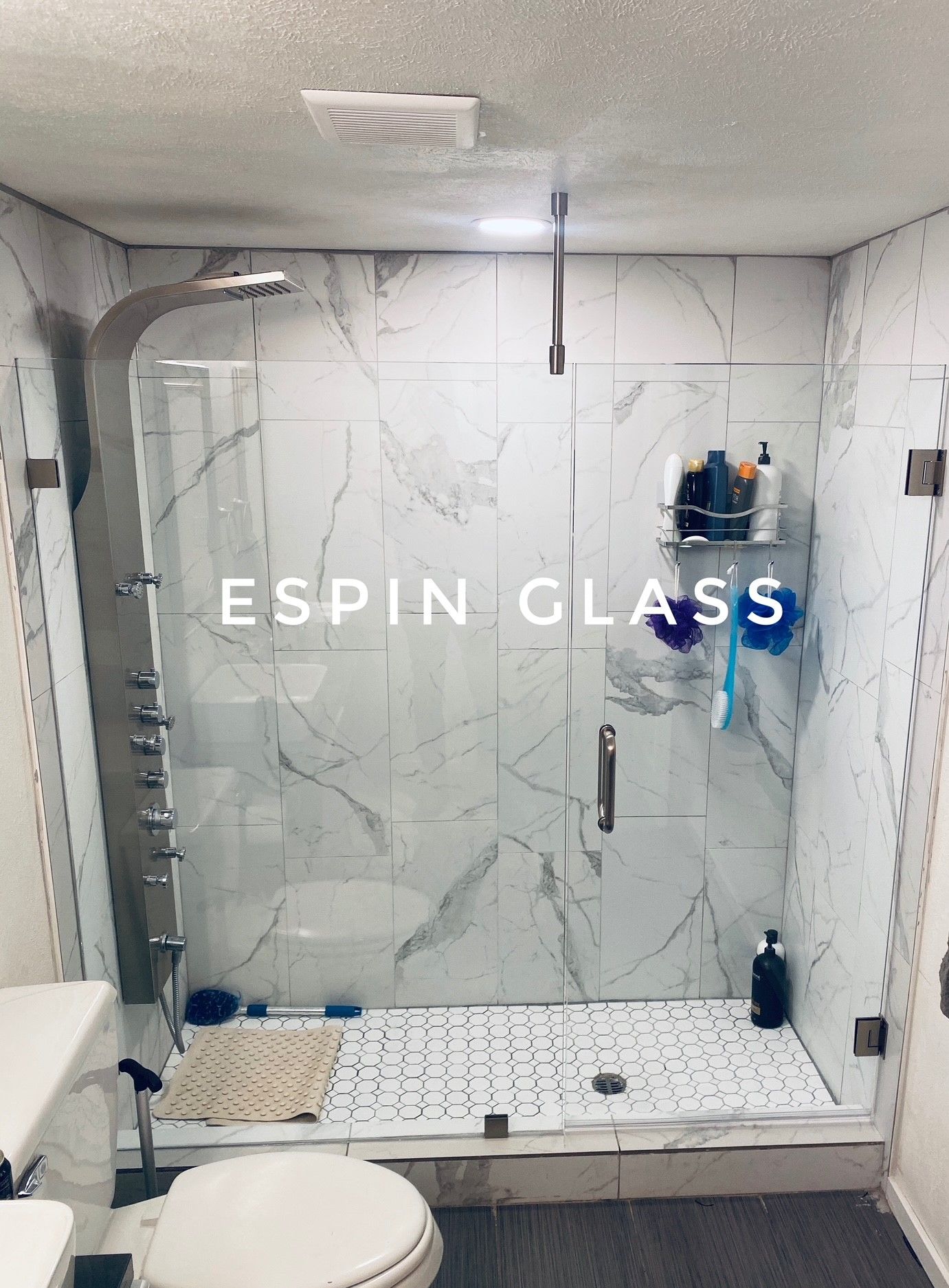 Shower enclosure with glass doors, marble tile, and chrome fixtures.