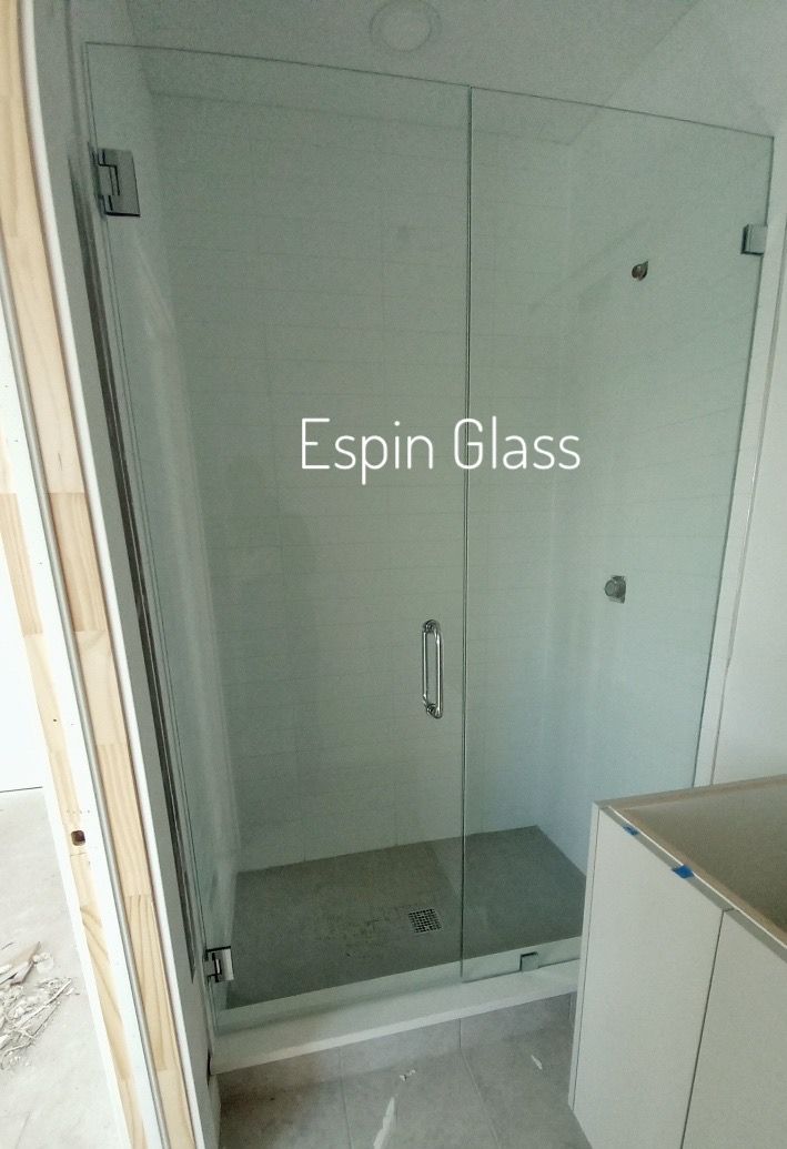 Glass shower enclosure with a door and a handle, in a modern bathroom.