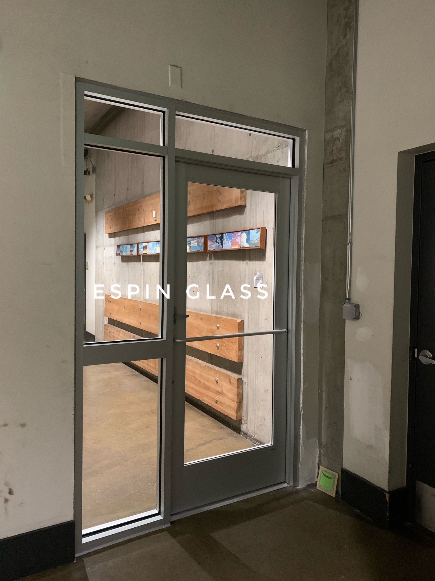 Exterior of ESPIN GLASS entrance with glass door and side panel, gray metal frame.