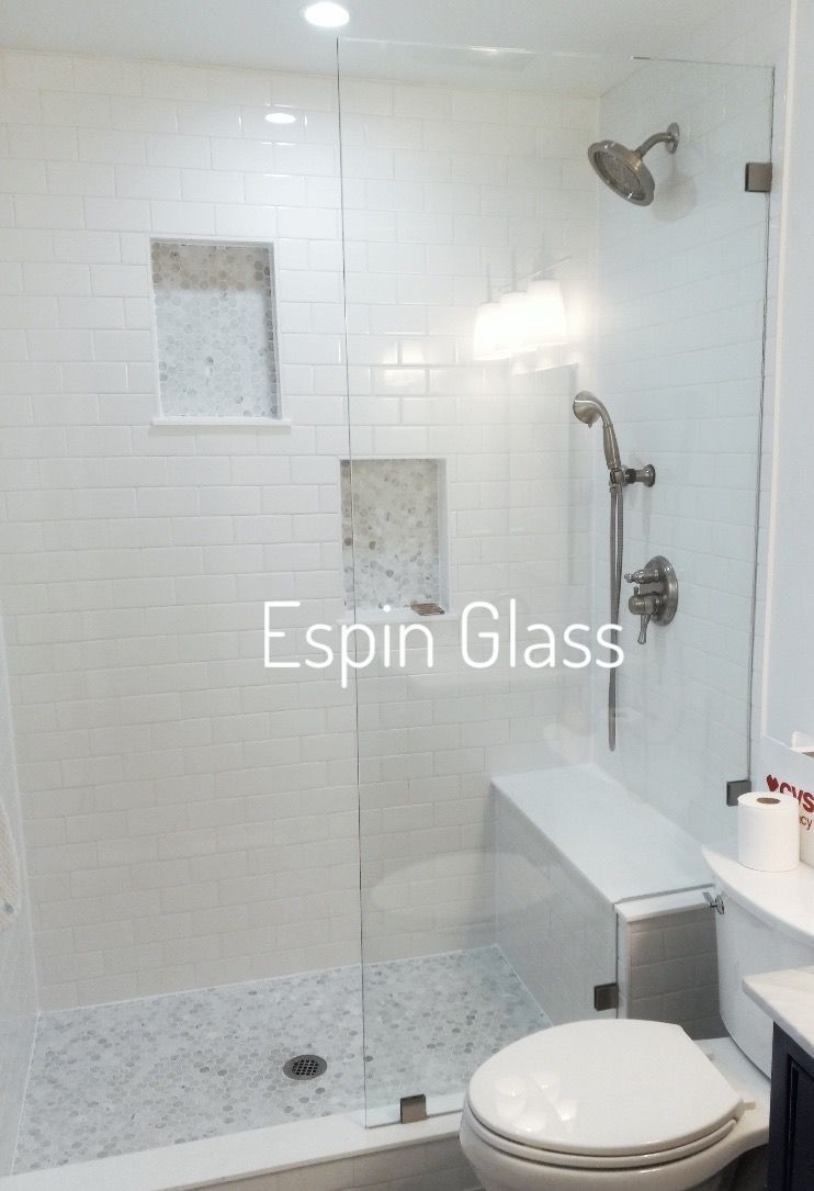 Glass shower with white tile walls, marble floor, a bench, and a toilet.