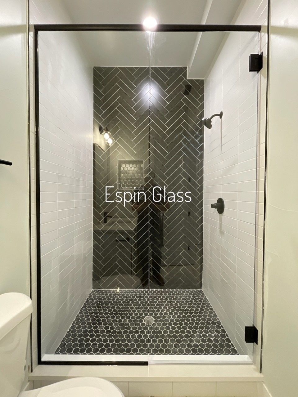 Shower with glass door and black hardware, patterned tiles, and the text 