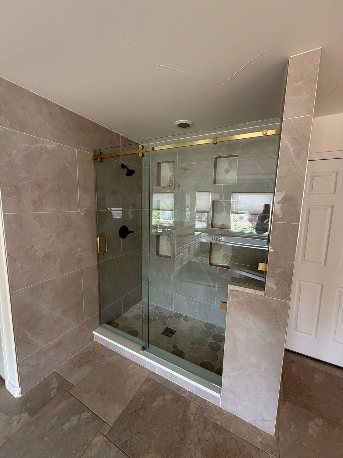 Walk-in shower with glass enclosure, tiled walls, and a bench in a modern bathroom.