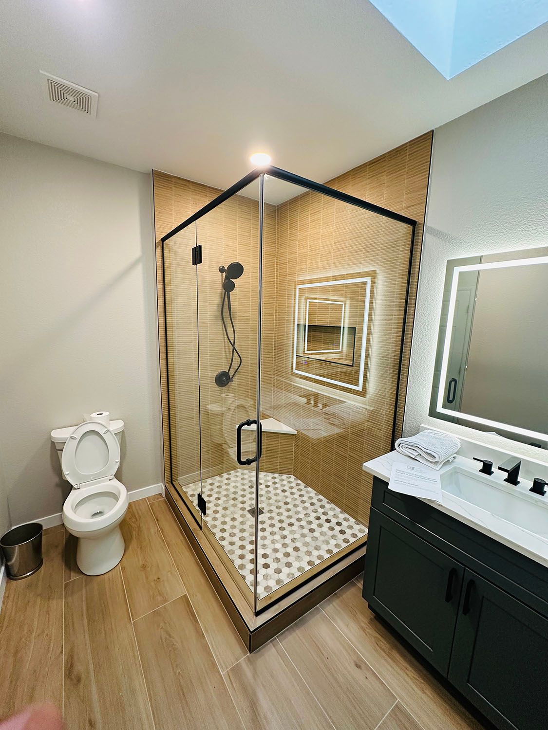 Bathroom with glass shower, toilet, and vanity in a bright, modern tiled space.