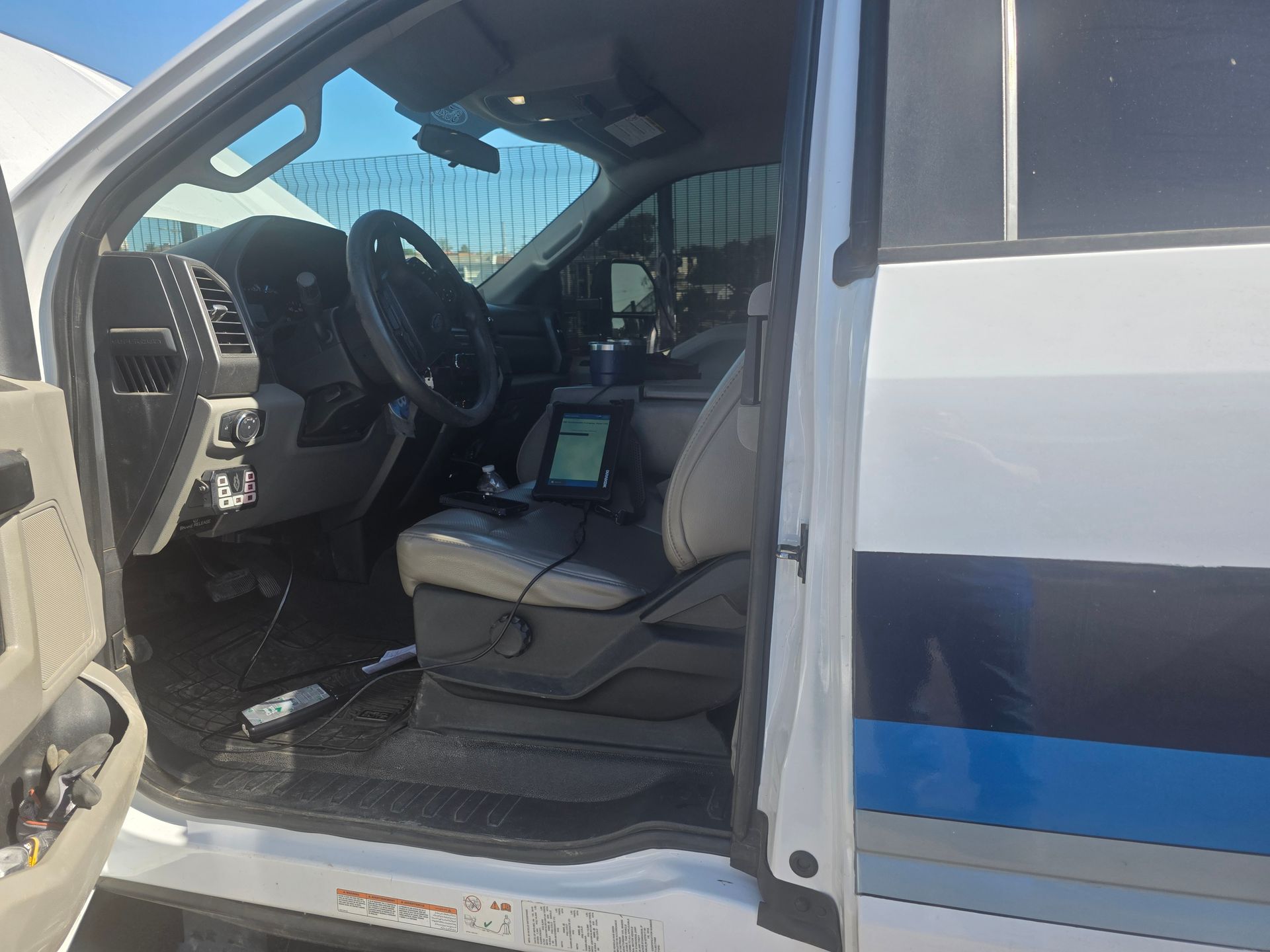 Open truck door showing beige interior, steering wheel, and center console with a mounted device.