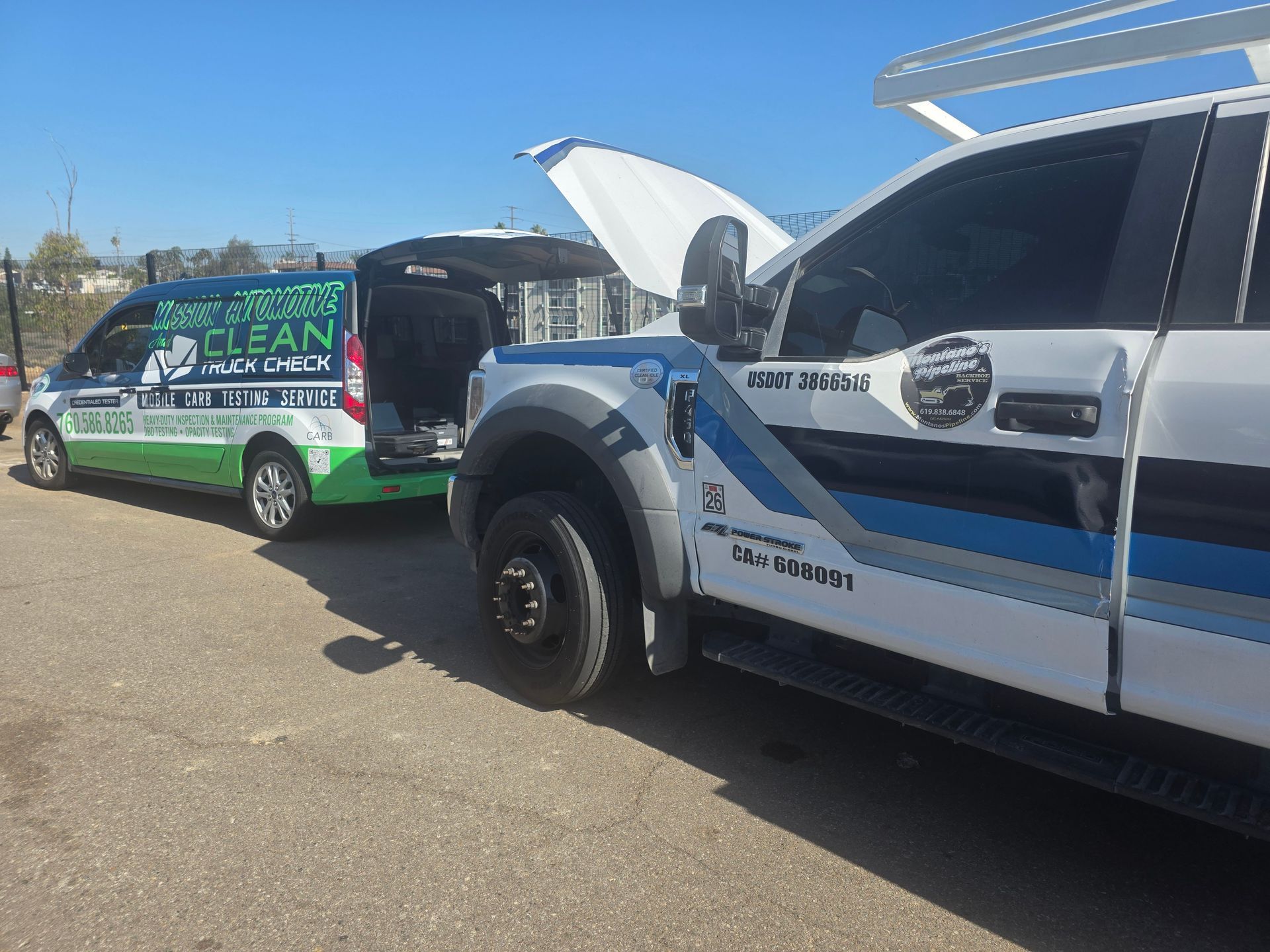 Two service trucks parked outdoors, one with hood open and the other with green Clean Energy branding