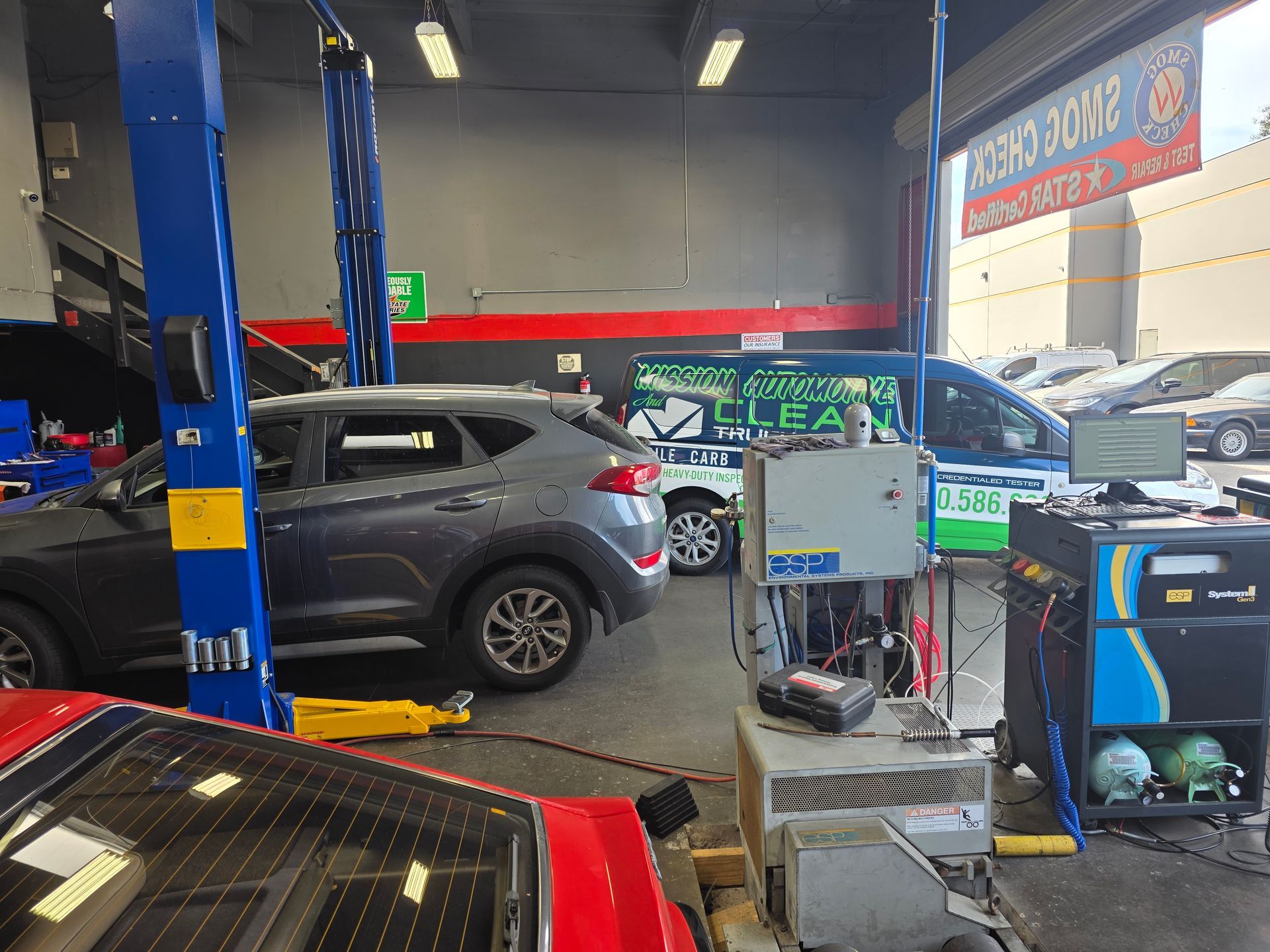 Auto repair shop with cars on lifts and parked inside, tools and equipment visible.