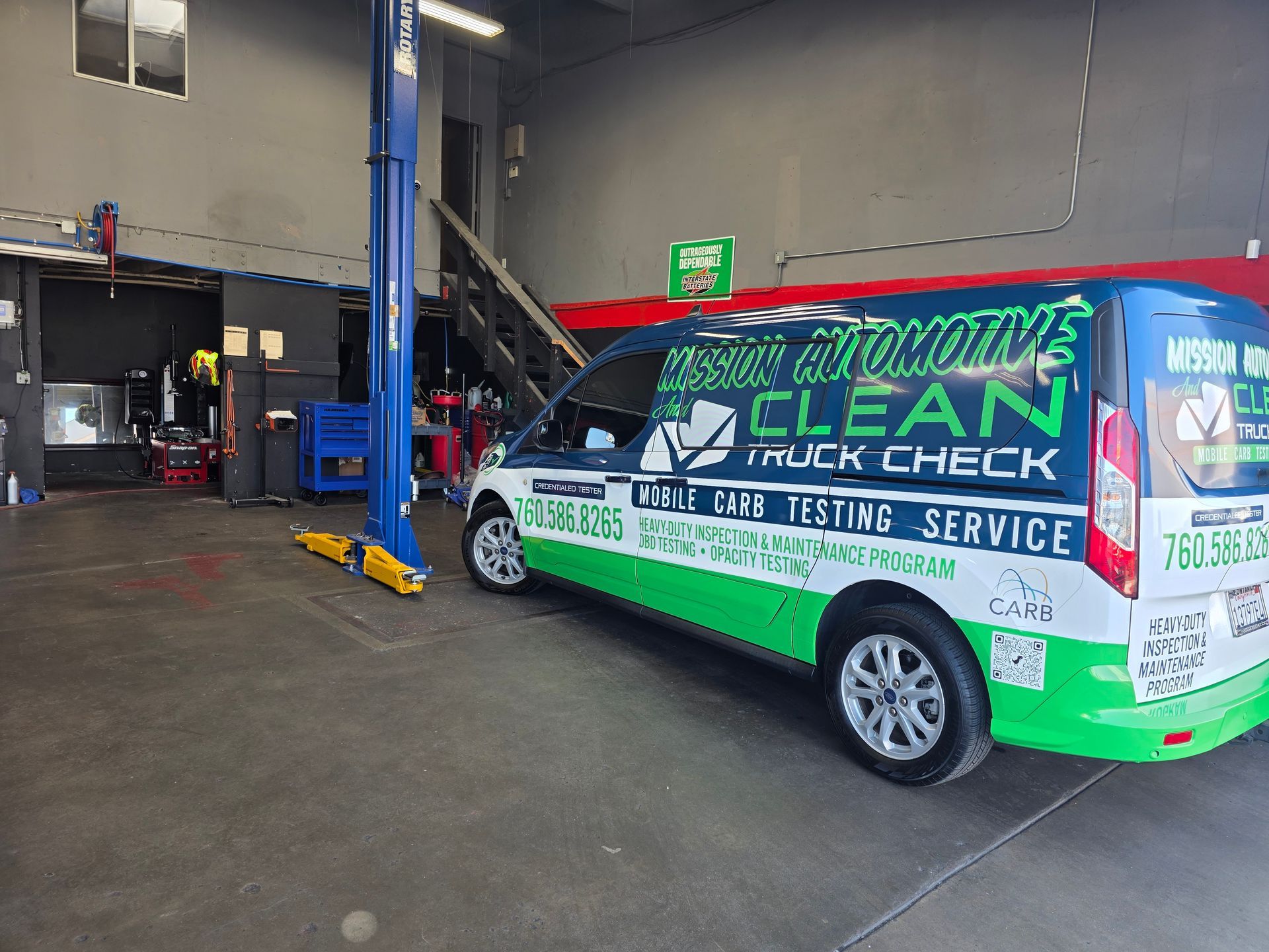 Green-and-white mobile windshield cleaning van inside an auto shop garage