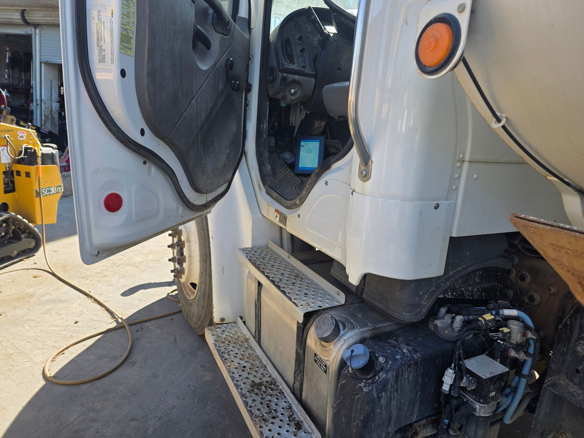 Open truck cab with side steps and fuel tank in a construction yard