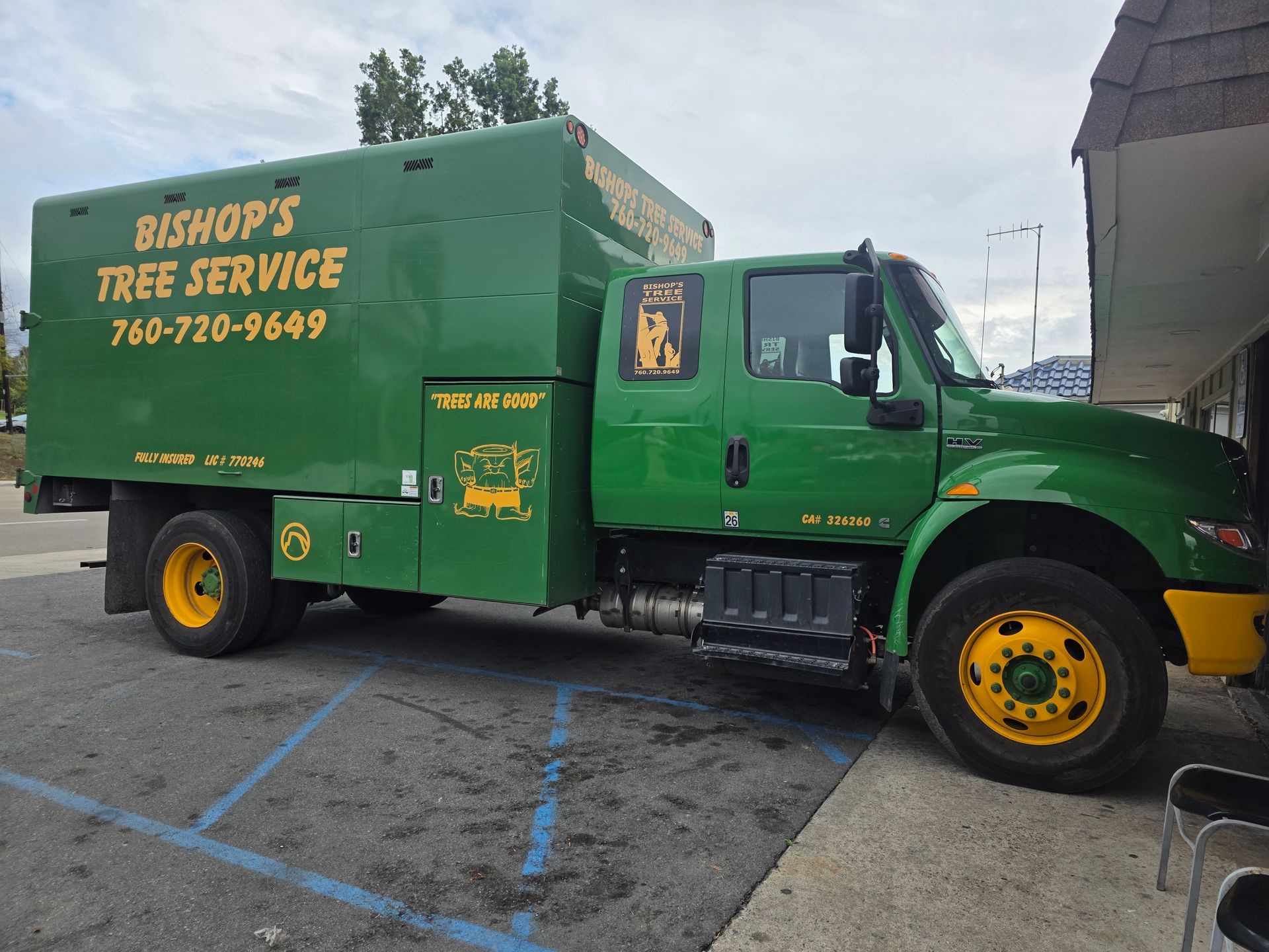 Green Bishop's Tree Service truck parked outdoors under an overpass.