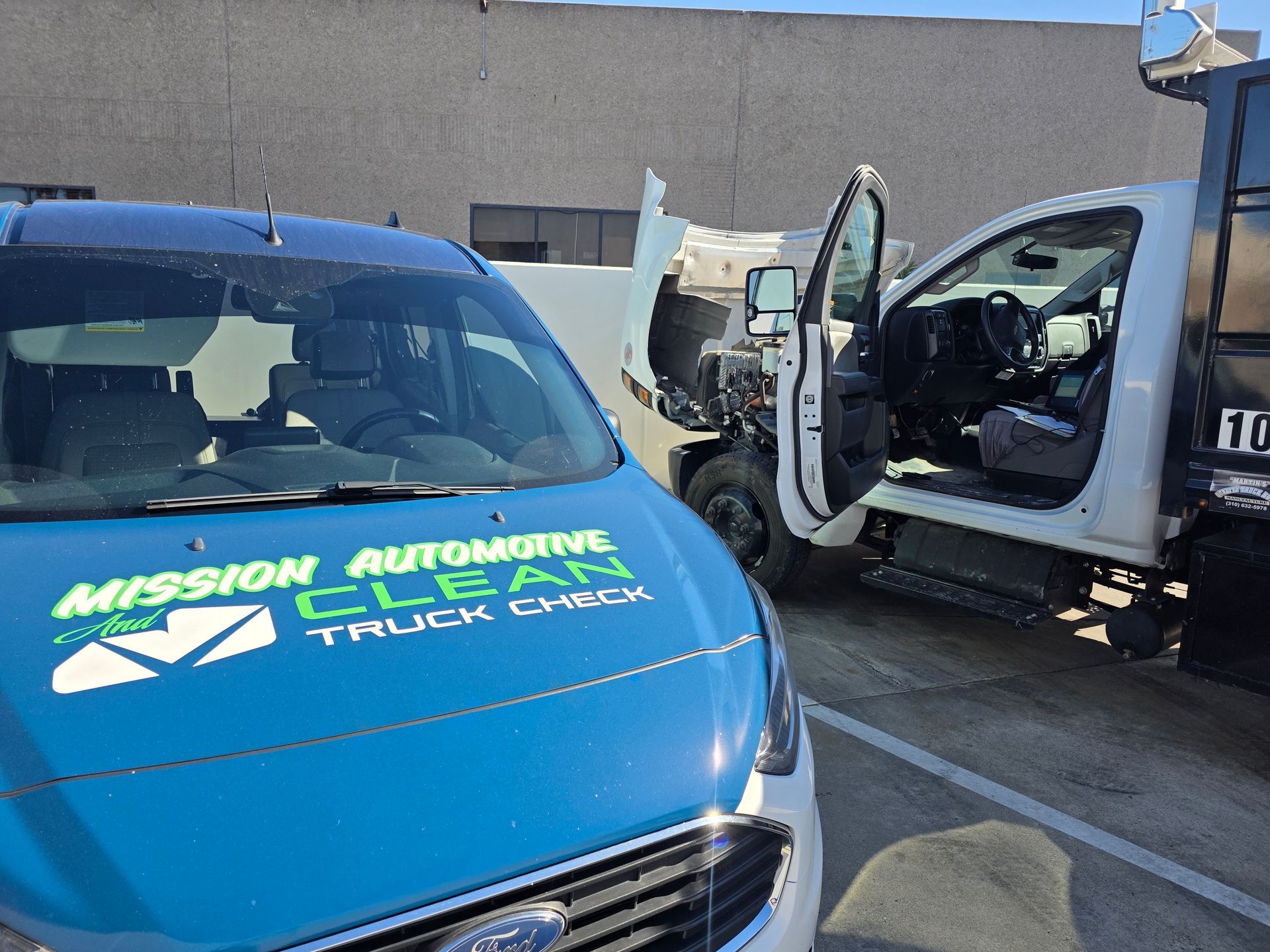Blue Mission Automotive service van beside damaged white truck in a parking lot