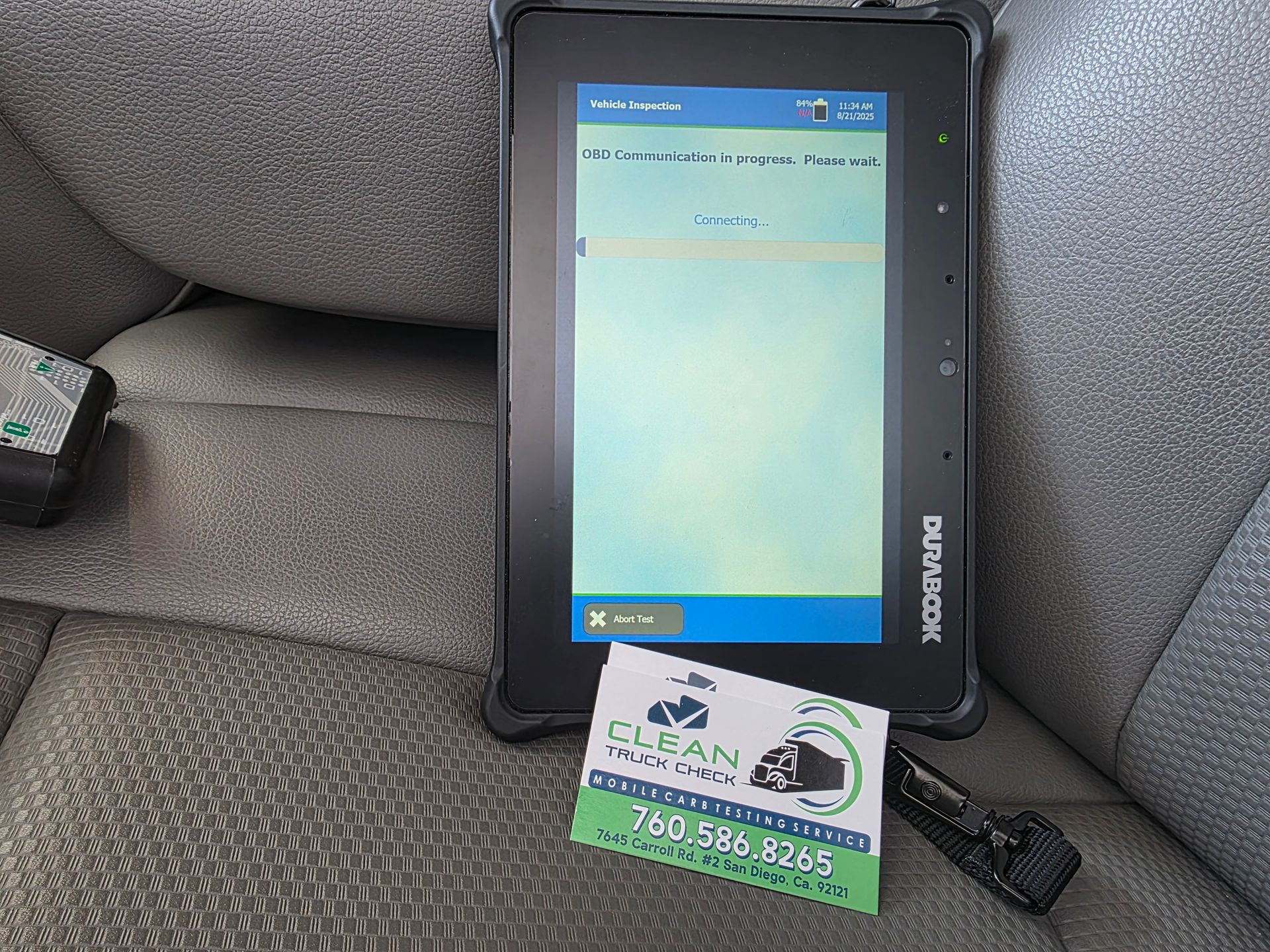 Car dashboard with a mounted GPS/navigation screen and a business card resting below it.