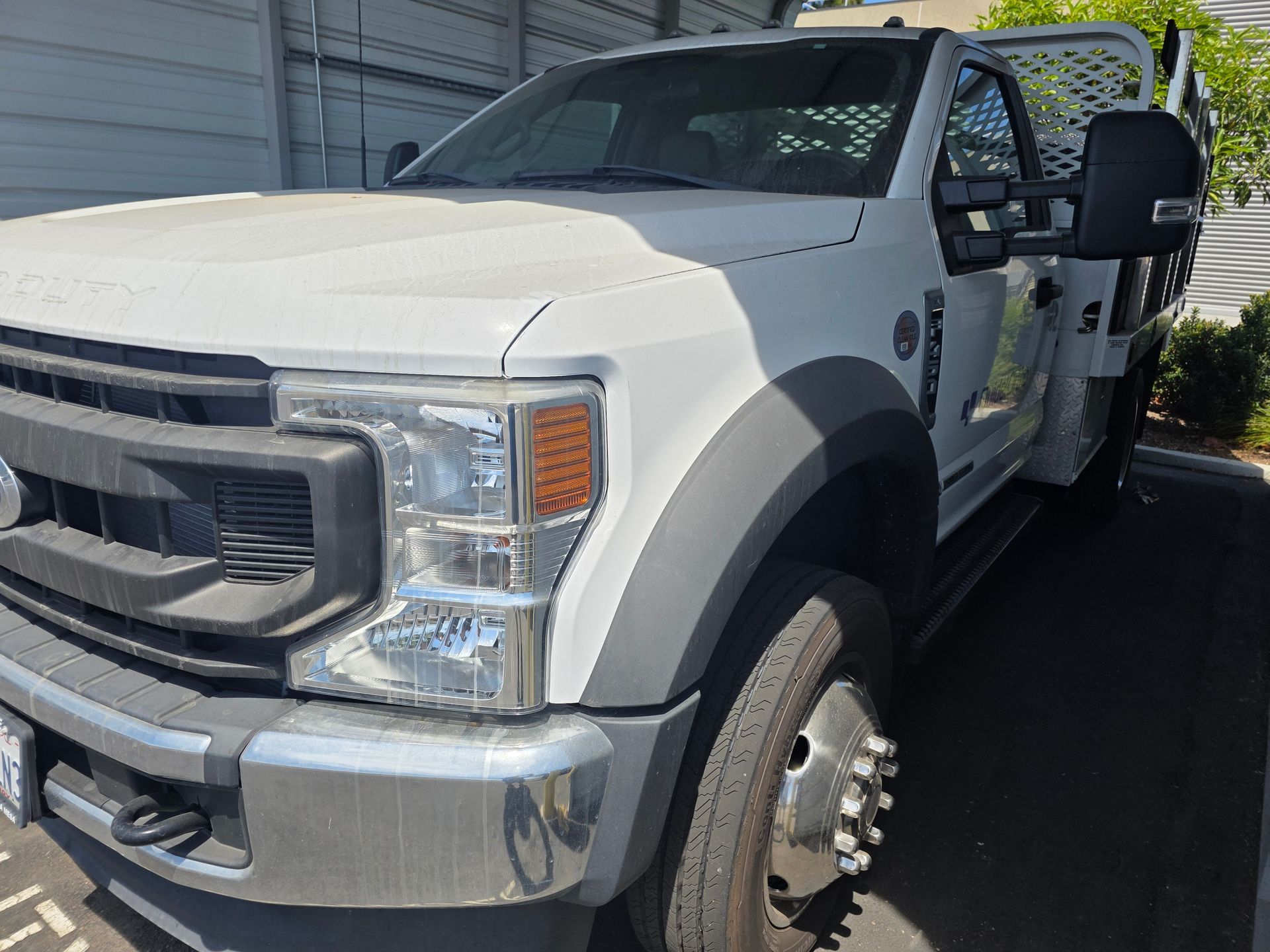 White pickup truck parked outdoors beside a building, with its driver door open.