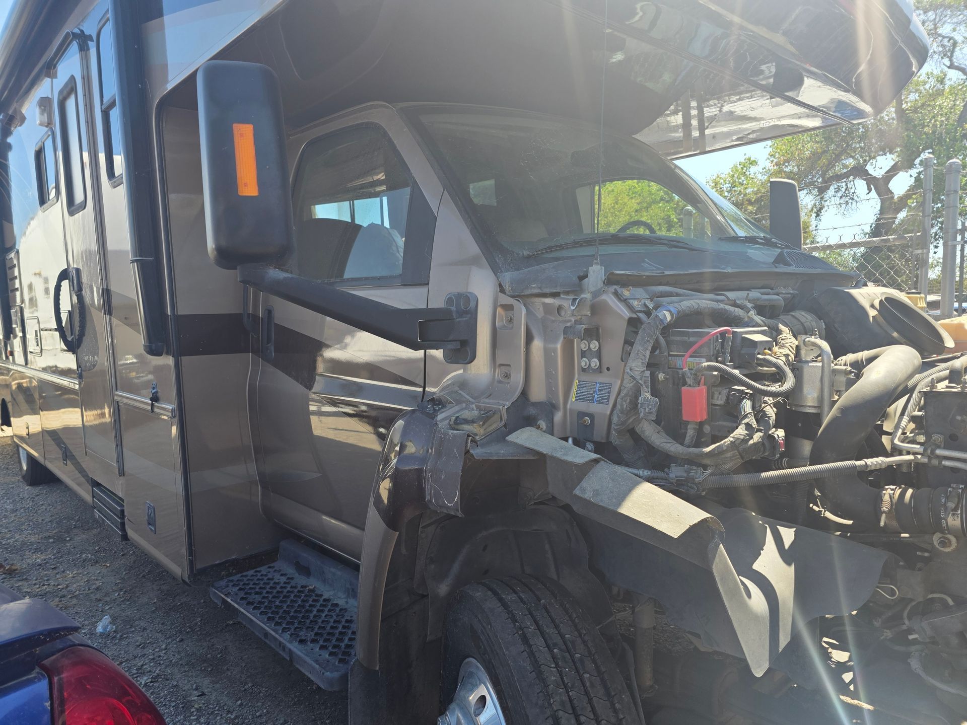 Damaged black semi-truck cab with exposed front engine after a collision