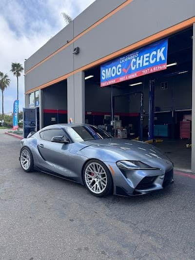 Silver sports car parked outside a smog check garage