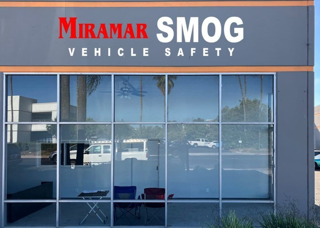 Miramar Smog vehicle safety storefront with large gray and orange sign and reflective windows