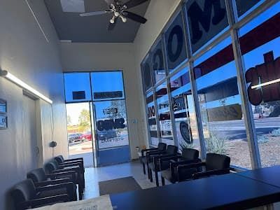 Modern lobby with black chairs, glass storefront windows, and bright blue daylight outside