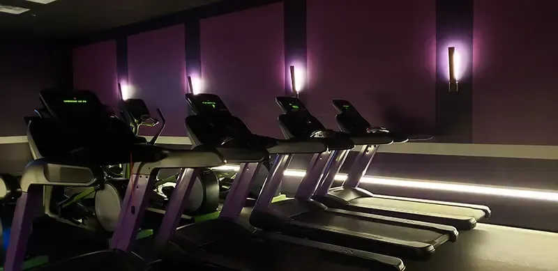 a row of treadmills in a gym with purple walls