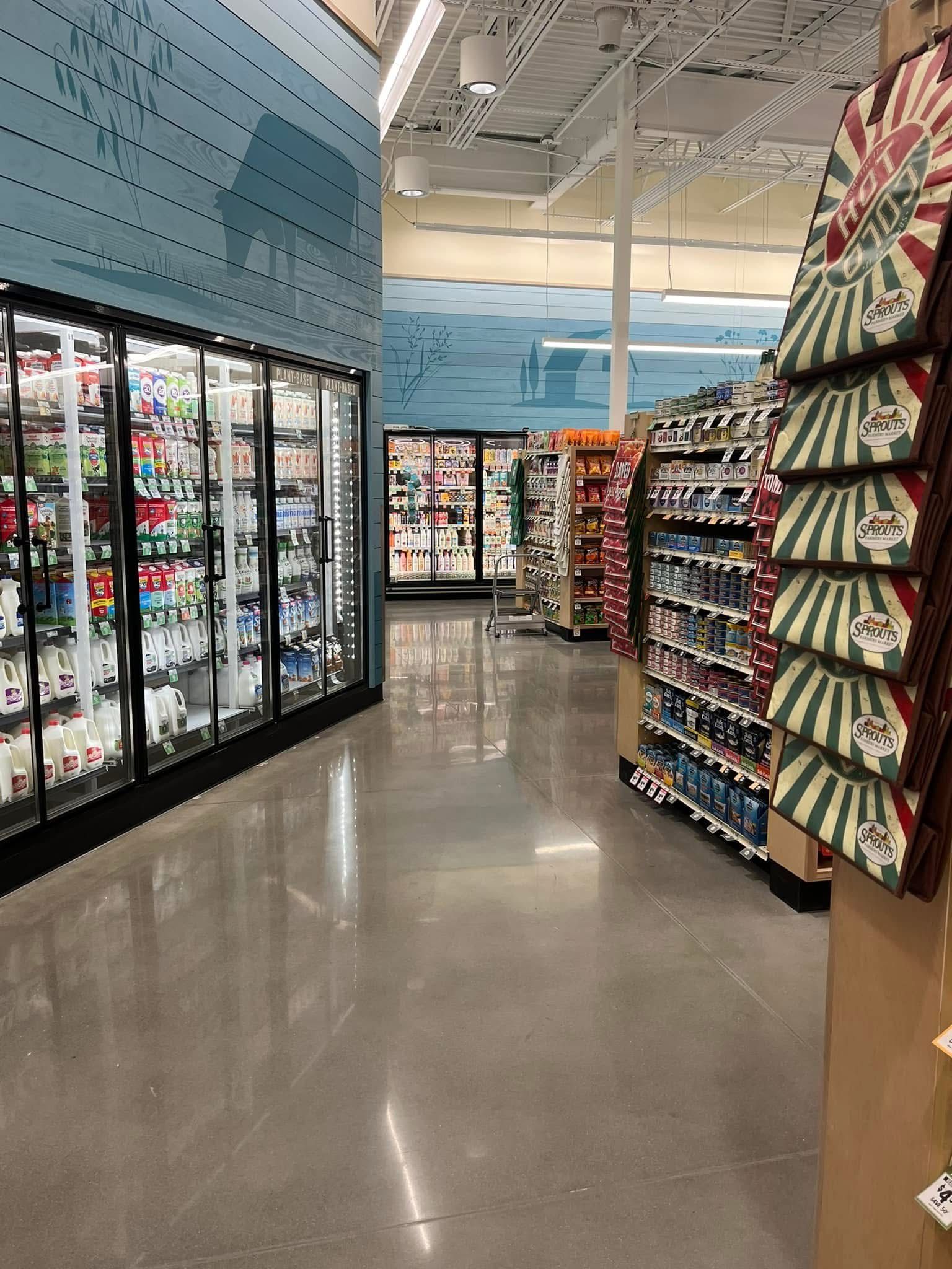 Grocery store aisle with refrigerated drinks on the left and shelves of chips on the right