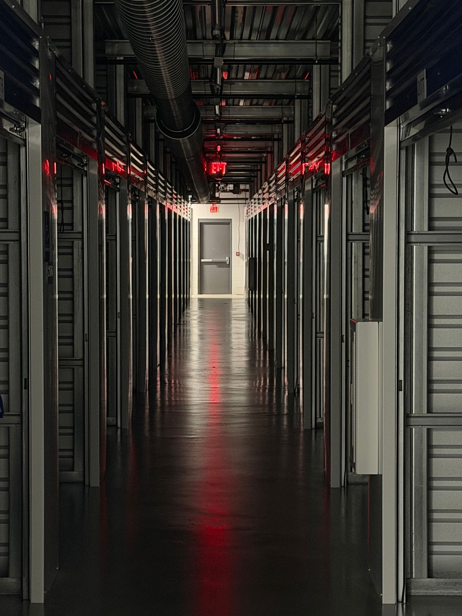 Dim data center corridor with rows of server racks and red indicator lights