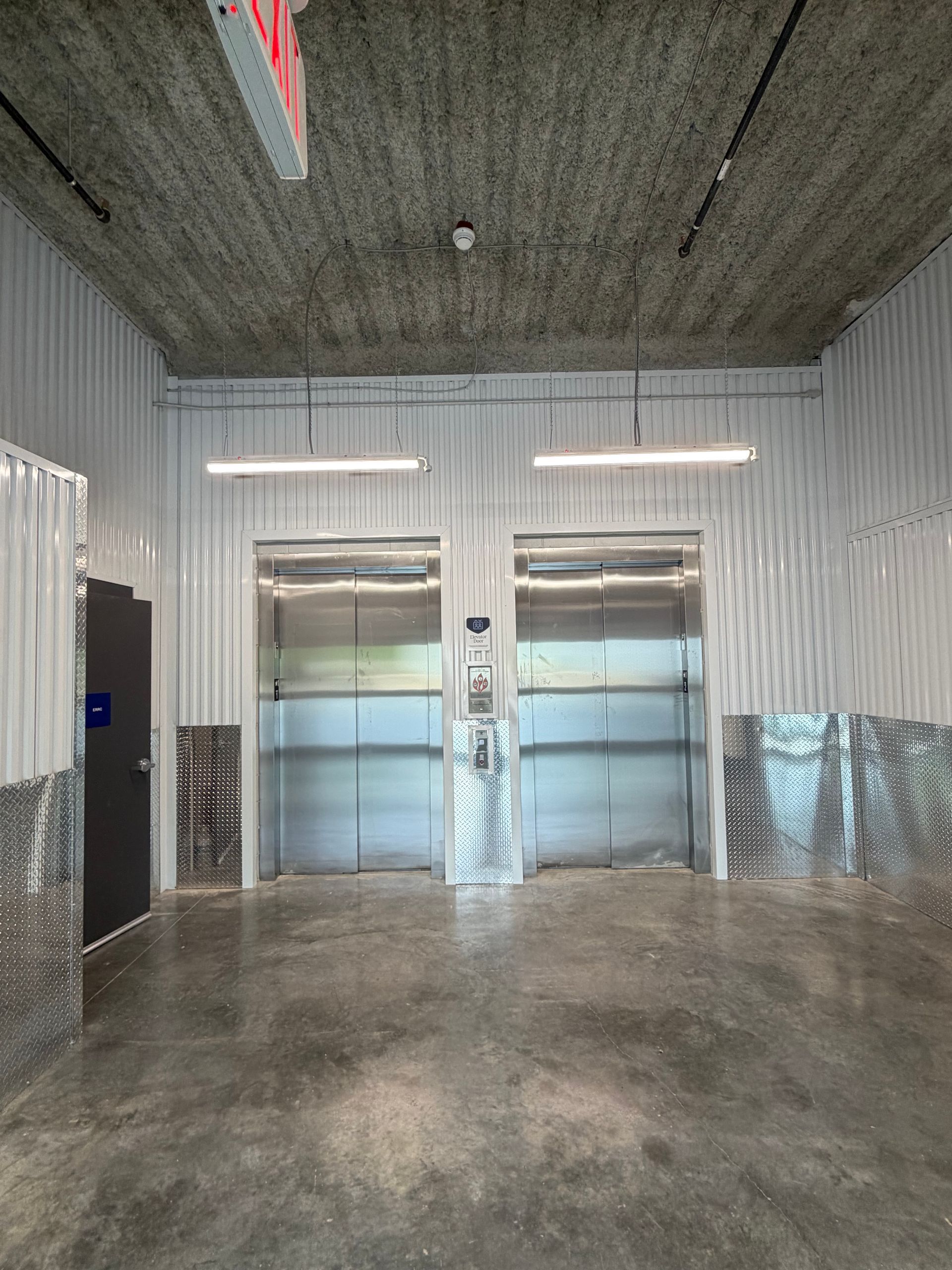 Empty industrial room with two silver elevators and a concrete floor