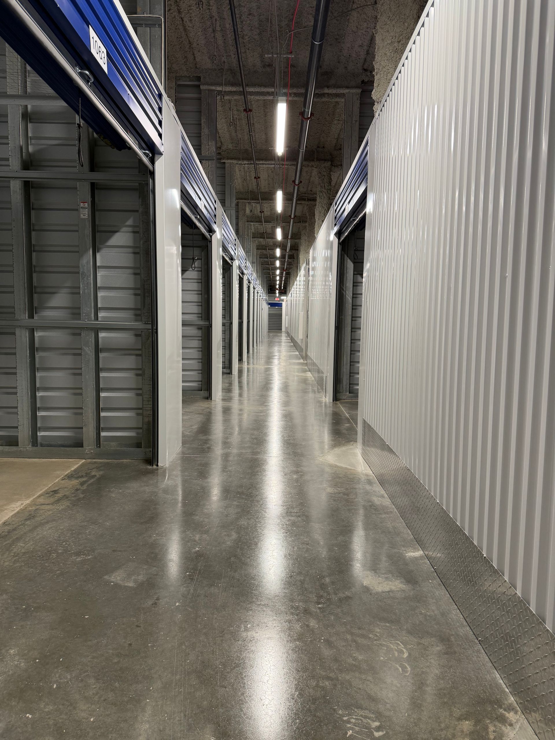 Long warehouse corridor with storage units and a polished concrete floor