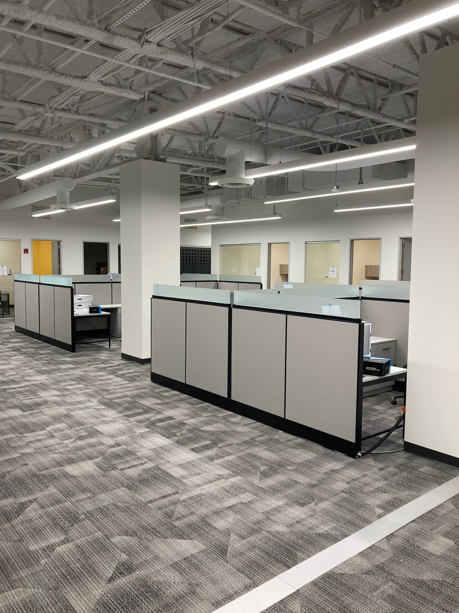 Empty office cubicles under bright ceiling lights in a modern workspace