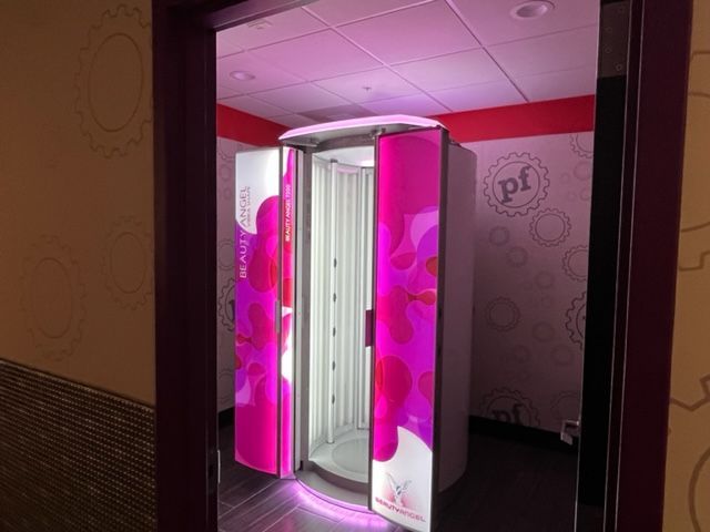 Pink-lit tanning booth in a small salon room