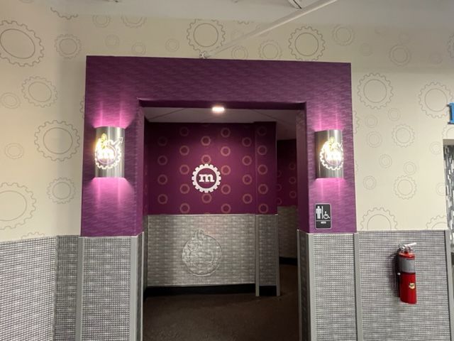 Purple-branded restaurant entrance with wall sconces and tiled lower walls