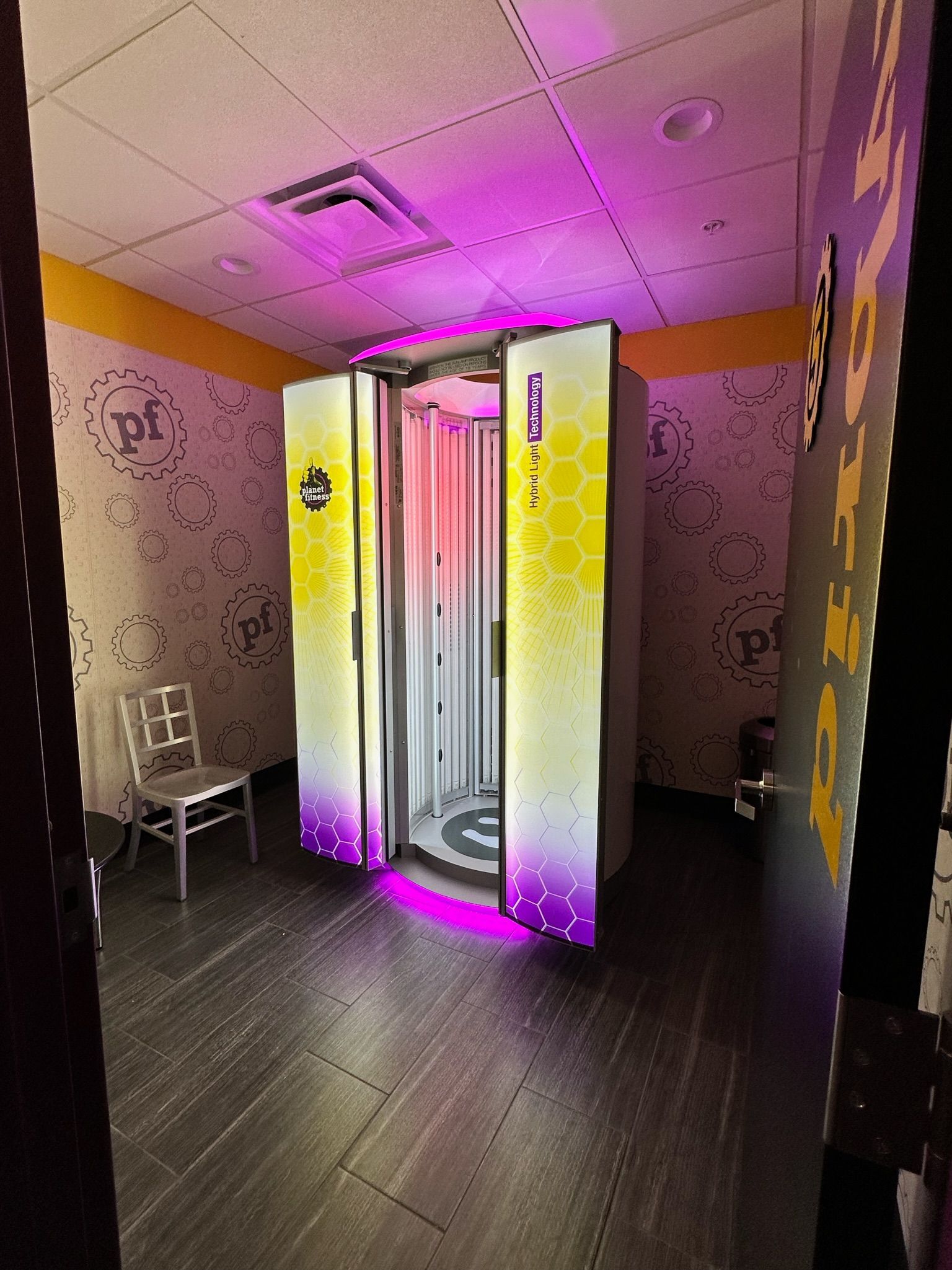 Spa room with a glowing pink-and-yellow shower pod and a chair in the corner