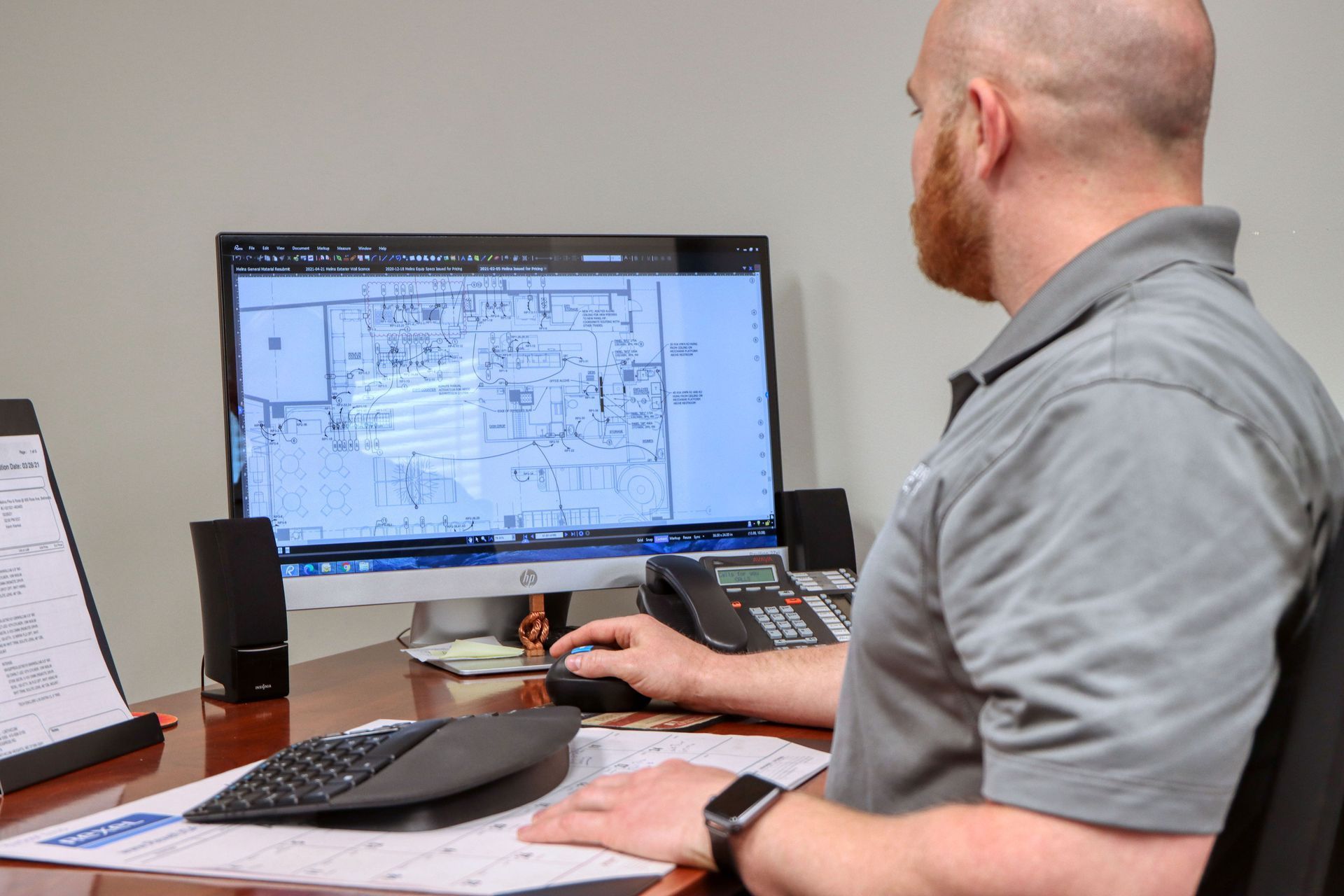 a man is sitting at a desk looking at a computer screen