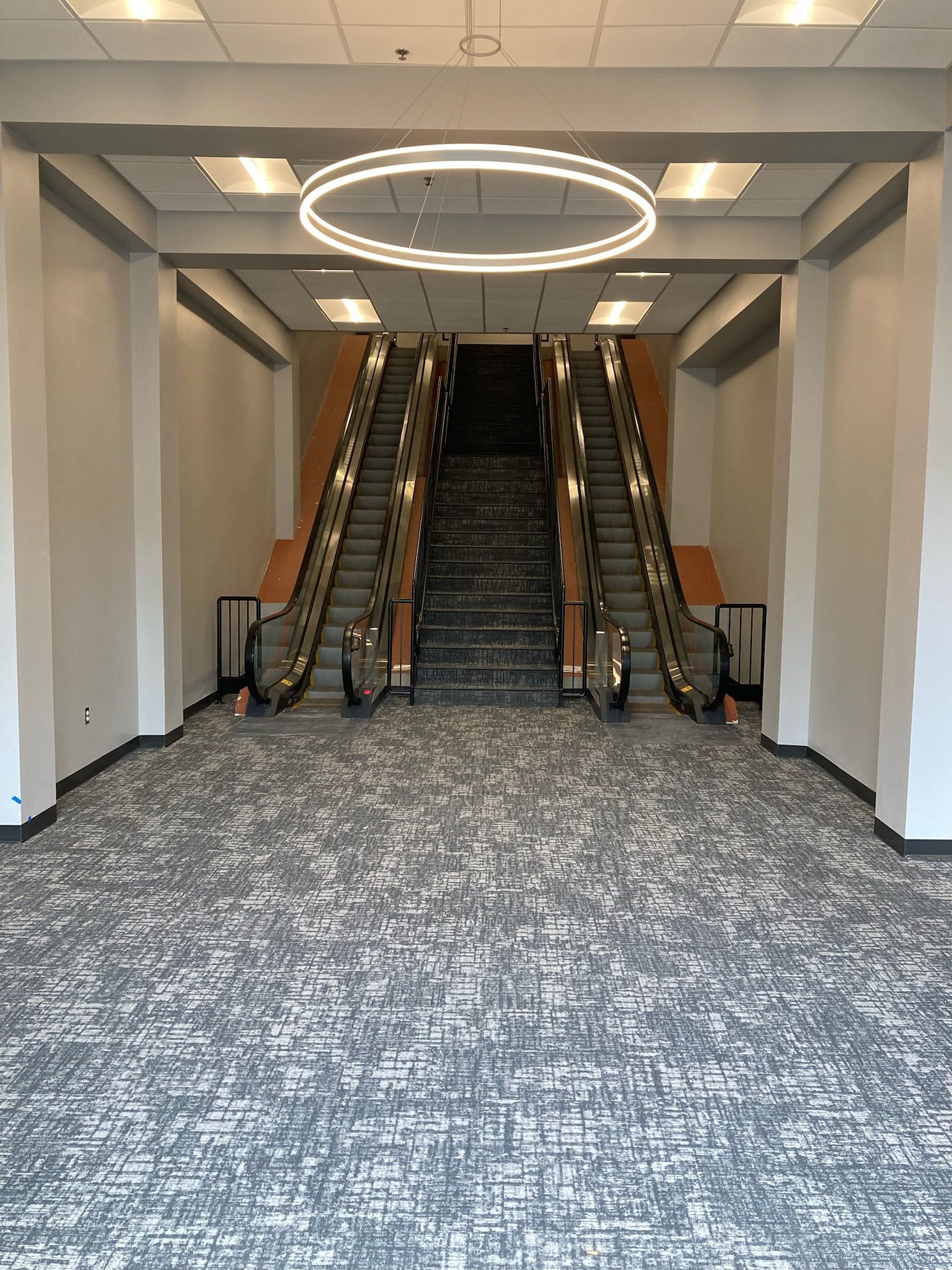 a large empty room with an escalator and stairs