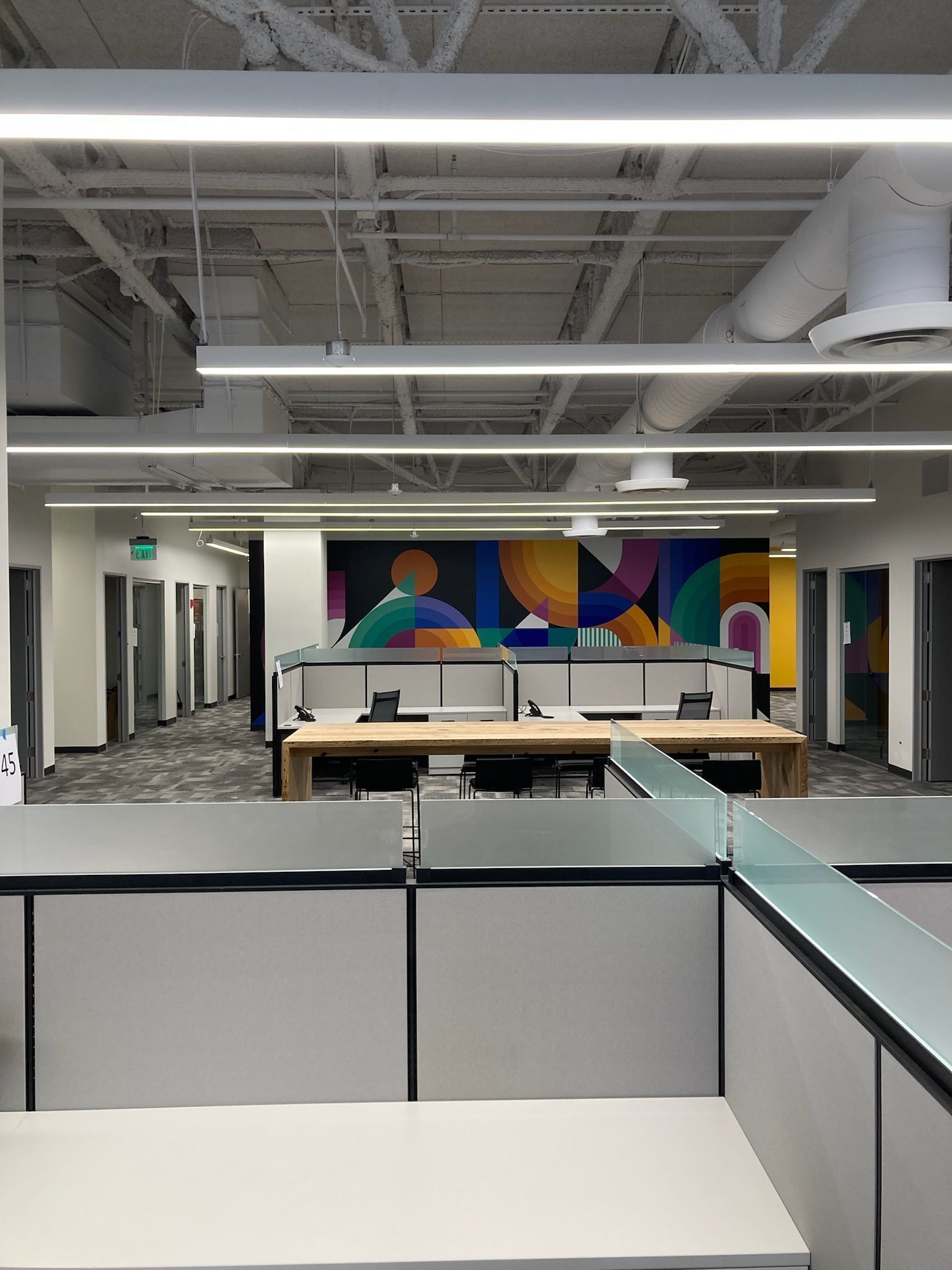 an office with cubicles and a large painting on the wall