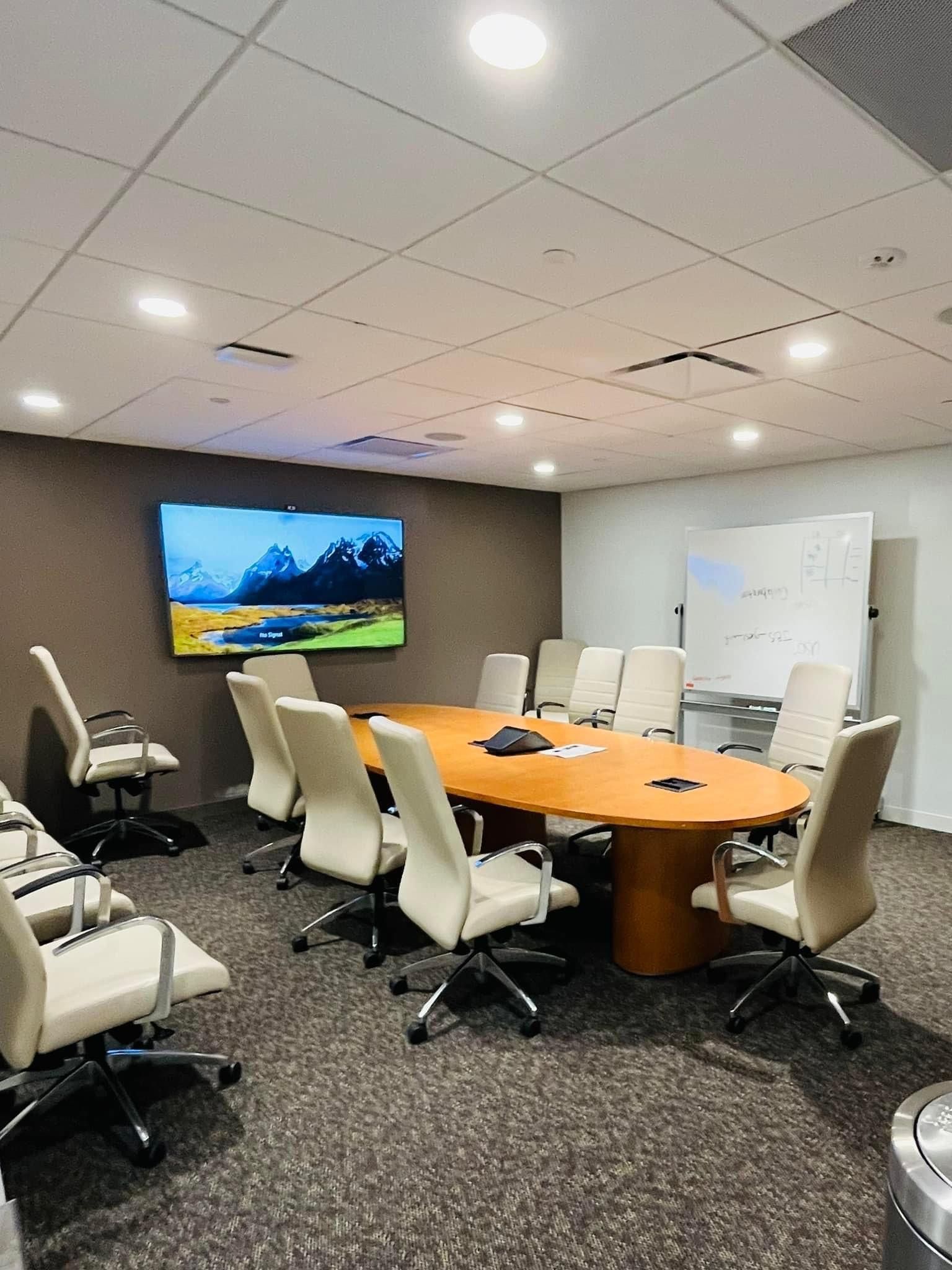 a conference room with a long table and chairs and a flat screen tv on the wall