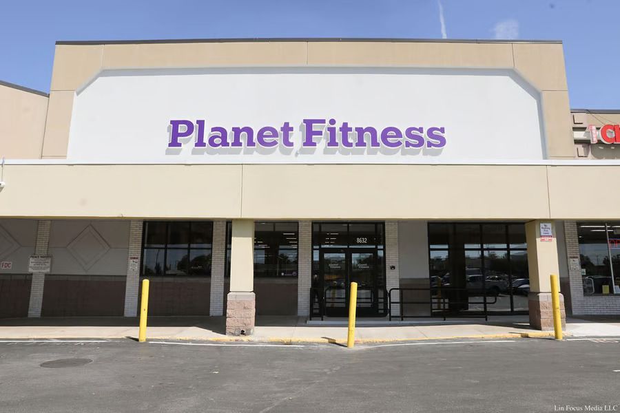 Planet Fitness storefront with purple sign and glass entrance under a beige facade