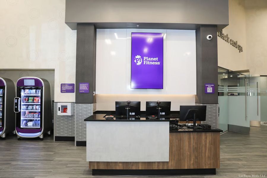 Airport check-in counter with a purple Frontier Airlines sign and self-service kiosks