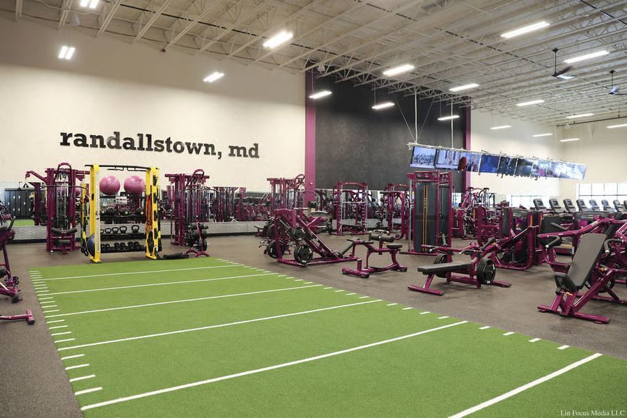 Large indoor gym with turf lane, exercise machines, and “randallstown, md” on the wall