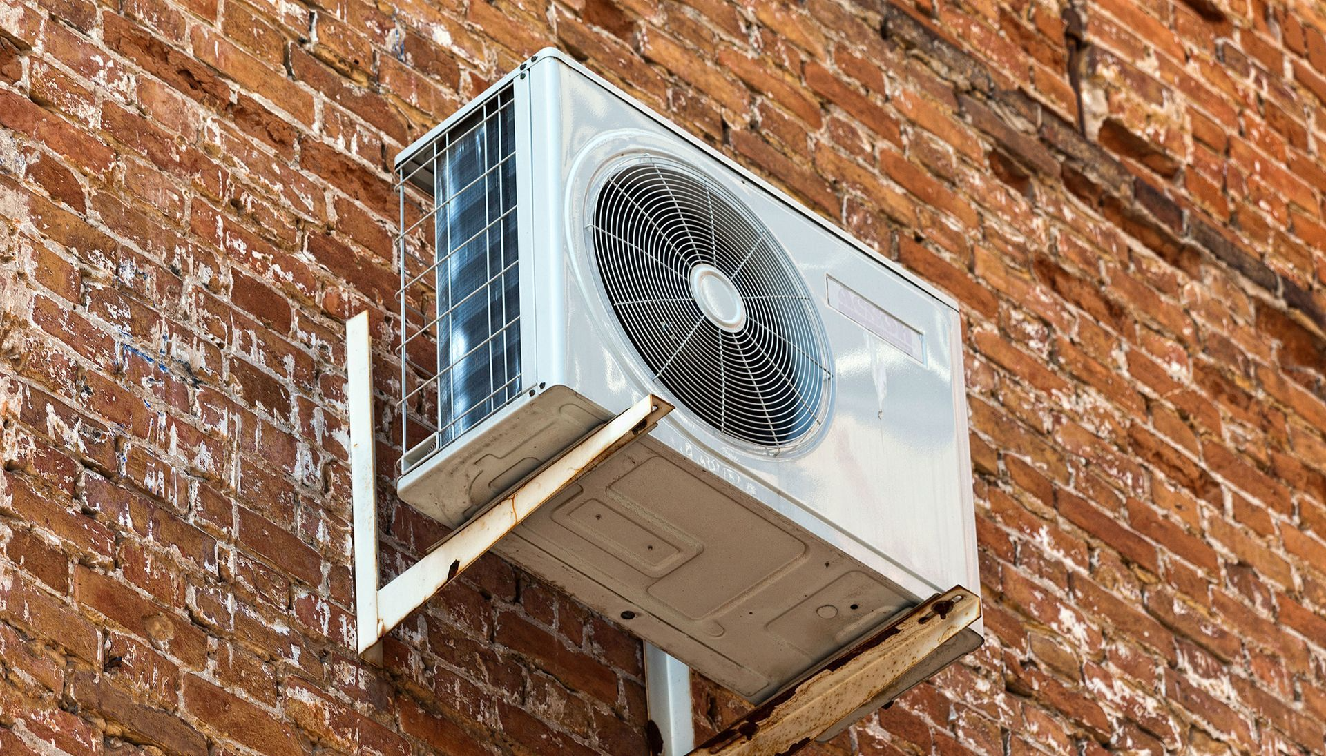 Air conditioning unit mounted on a brick wall.