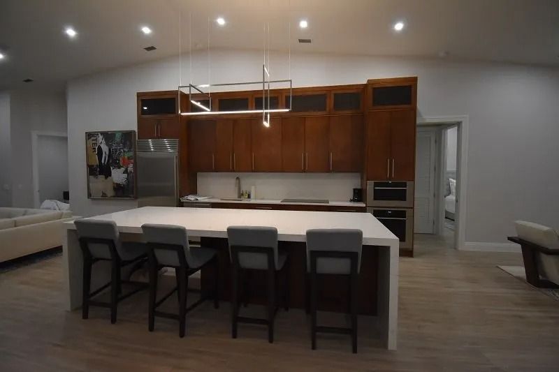 Modern kitchen with a large island, wooden cabinets, and pendant lighting; bar stools.