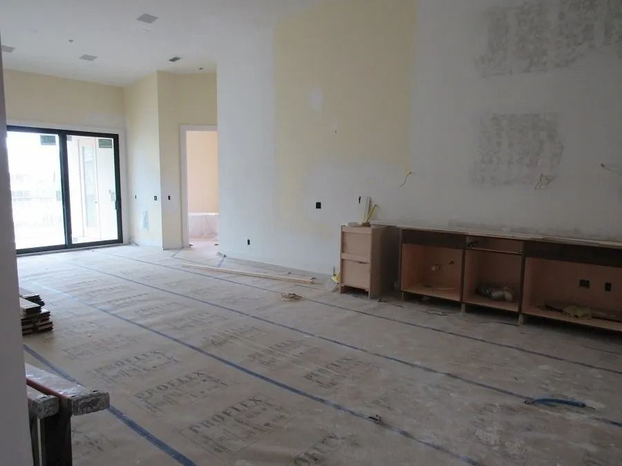 Interior of a room under construction, unfinished walls, cabinetry, sliding glass doors, bare floor.