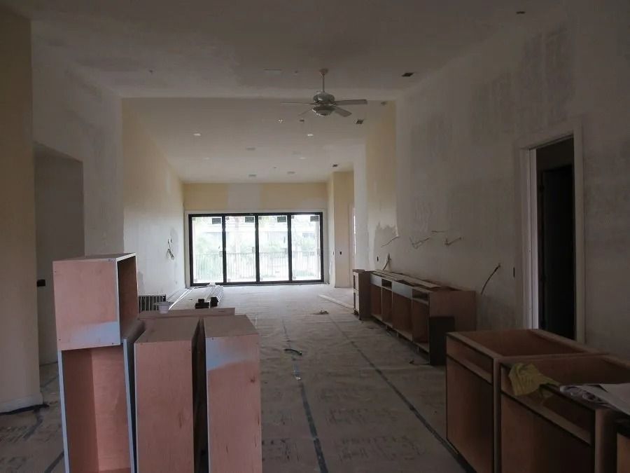Interior of a room under construction: bare walls, cabinets, and sliding glass doors with a fan in the middle.