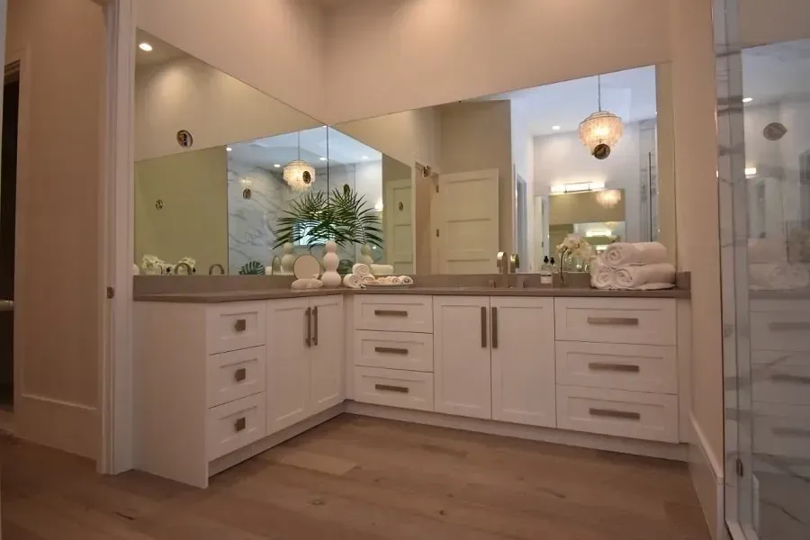 White bathroom vanity with mirrors and light-colored wood floor.