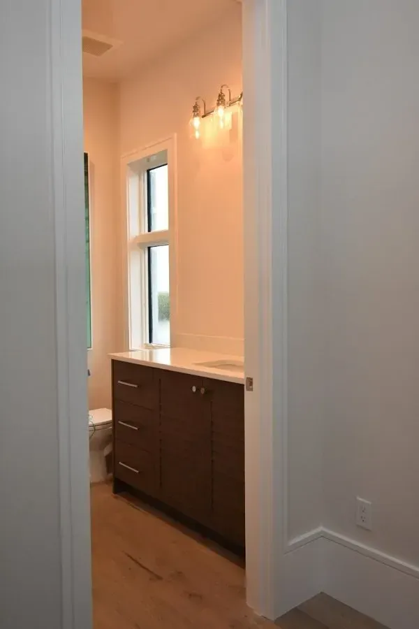 Bathroom with a brown vanity, white countertop, and small window.