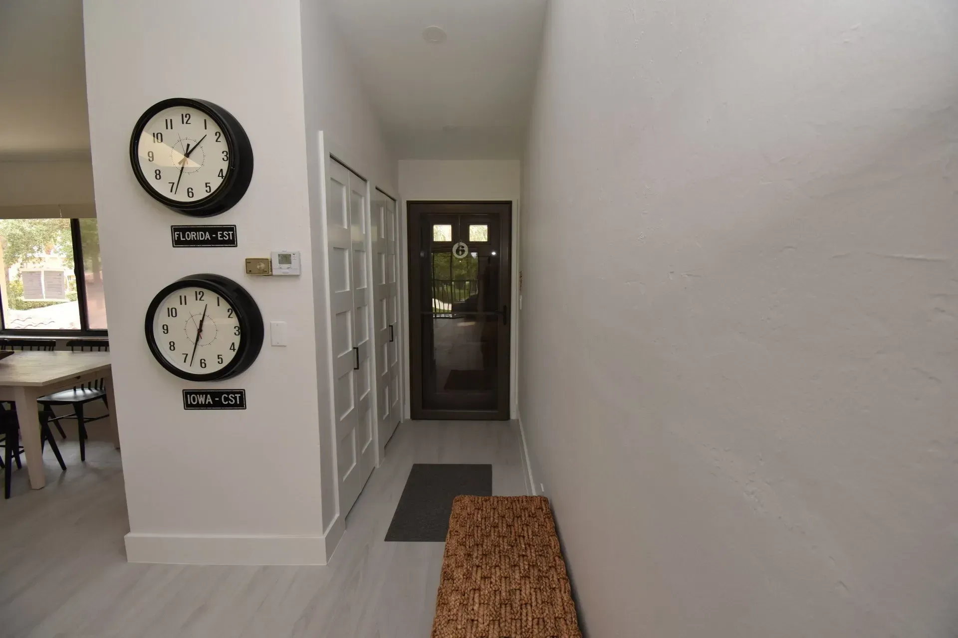 Hallway with clocks, closet doors, and a door at the end.