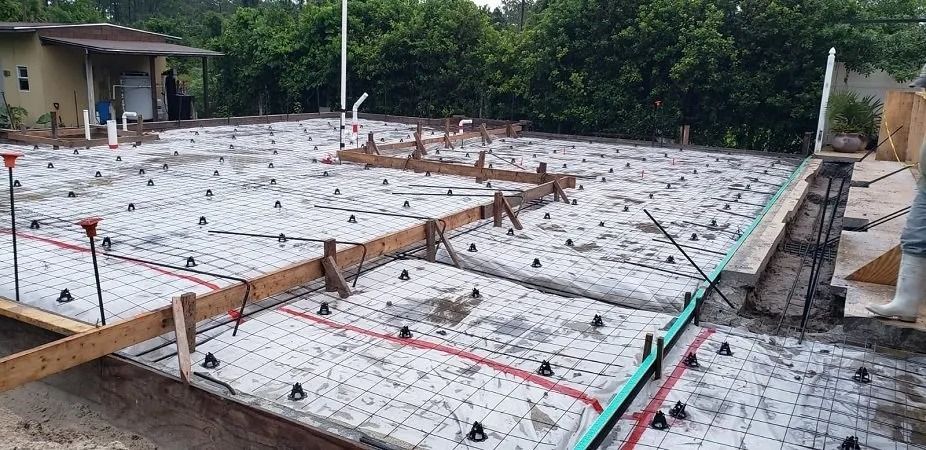 Concrete slab foundation construction site with formwork, reinforcing steel, and utilities.