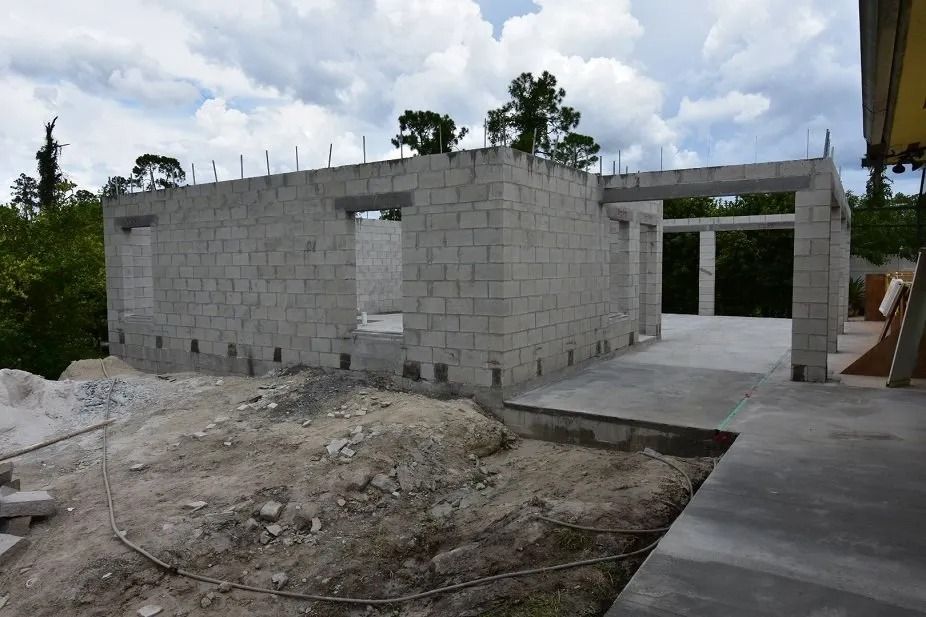 Construction site with concrete block walls and windows, under a cloudy sky.