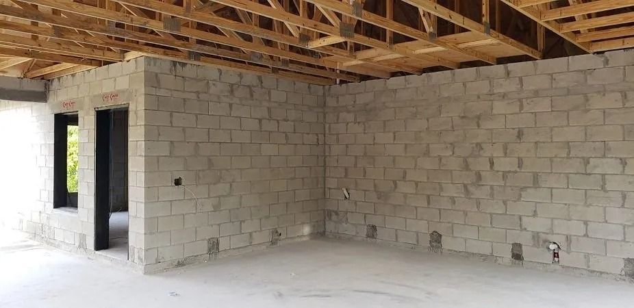 Interior construction: exposed block walls, unfinished wooden ceiling. Room with doorways and a window.